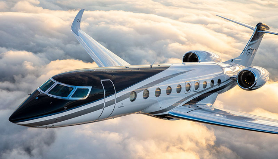 A sleek luxury private jet flying high above a sea of clouds during sunset, showcasing its modern design and elegance.
